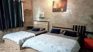 A room with two beds, a nightstand, a red bench, and a wall with a picture. - Ingna Resort (Chanuman)