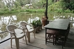 Eine Terrasse mit Tisch und Stühlen, Blumentöpfen und Blick auf ein Gewässer.