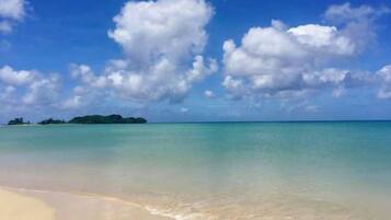 Uma praia com águas cristalinas e uma ilha ao longe.