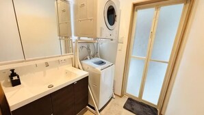 A compact bathroom with a sink, mirror, and a washing machine. - ZZOKIAI Blue Fish! Only 2 mins to beach by walk! Maximun 11 persons! (Itoman)