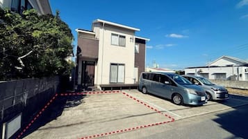 Uma área residencial com uma casa moderna de dois andares, um estacionamento e uma van estacionada.