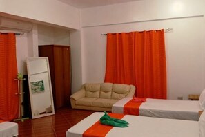 Une chambre avec deux lits, un canapé et des rideaux orange.