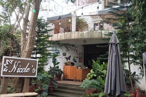A building with a sign reading 'Nicole's' and a covered entrance with steps leading up to it. - Nicole's Garden Naga (Naga)