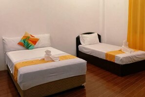 Deux lits simples avec du linge de lit blanc et une touche de jaune, un plancher en bois et un rideau jaune.