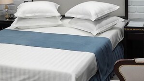 A bed with white bedding and a blue accent, a nightstand with a lamp, and a framed picture on the wall. - ZA'Faron Hotel Jizzax-Department of Management Only (Jizzakh District)