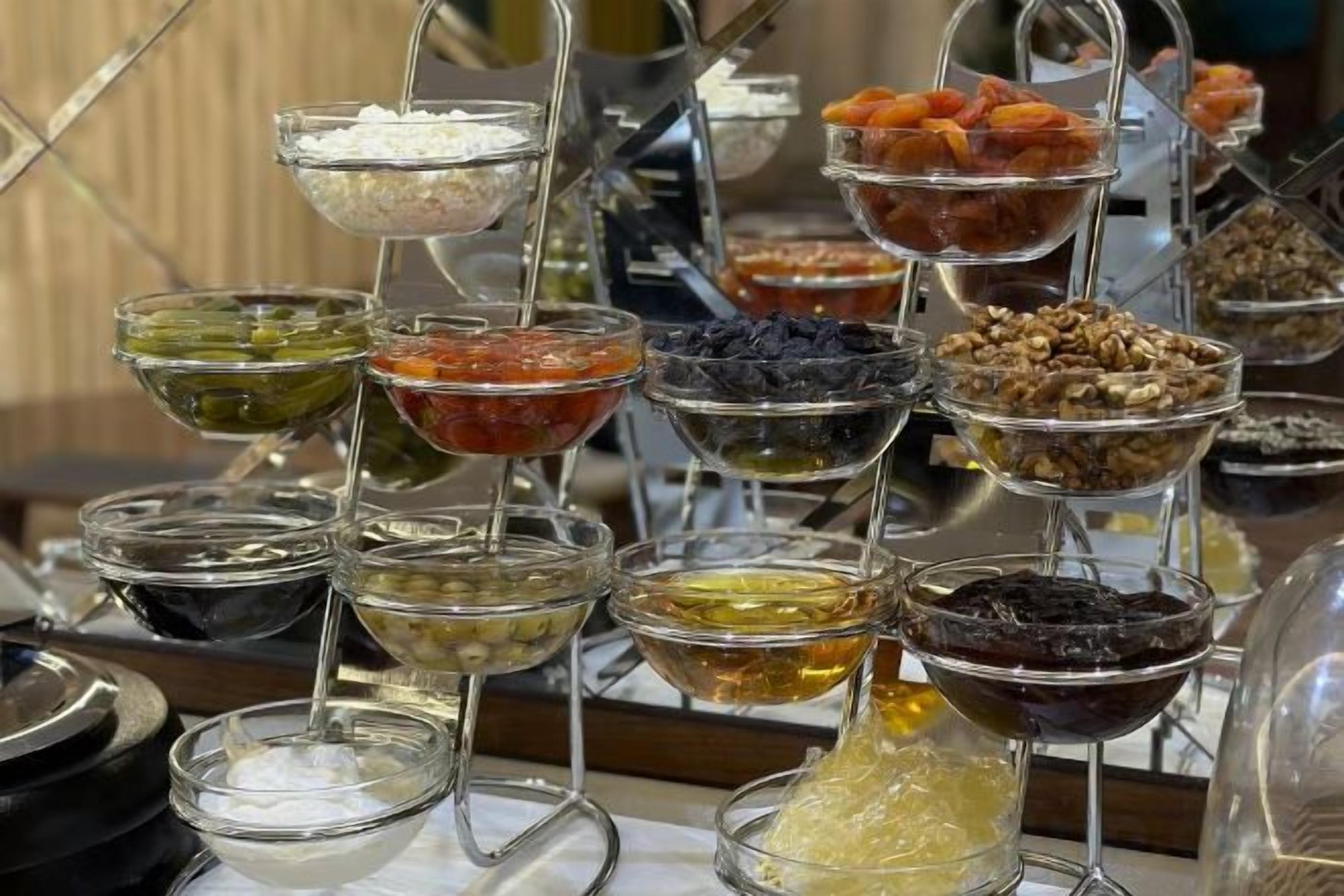A variety of food items displayed in clear glass bowls on stands.