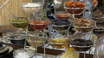 A variety of food items displayed in clear glass bowls on stands.