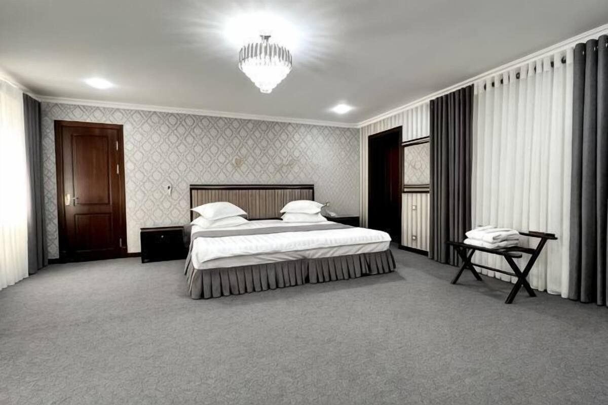 Een slaapkamer met een bed, nachtkastje en stoel.