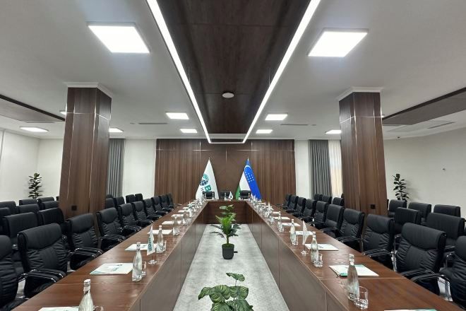 A conference room with a long table, chairs, and flags.