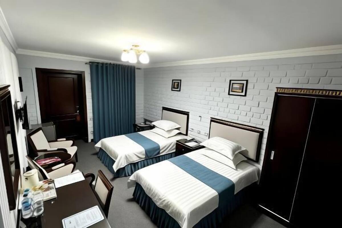 Een hotelkamer met twee bedden, een bureau, een stoel, een kledingkast en een deur.