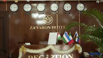 A reception desk with clocks, flags, and a garland.
