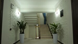 A hallway with white brick walls, a staircase, and potted plants. - ZA'Faron Hotel Jizzax-Department of Management Only (Jizzakh District)