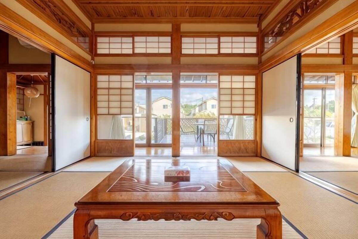 Une pièce de style japonais traditionnel, avec un sol recouvert de tatamis, des portes coulissantes et une table en bois.