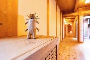 Un pasillo con pisos y paredes de madera, un pequeño adorno sobre un repisa de madera, y una puerta a la izquierda.