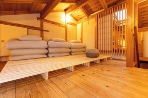 A wooden interior with a bench, pillows, and a stone. - MOKUSEKI - Nagoya Japanese Vacation House (Nagoya)