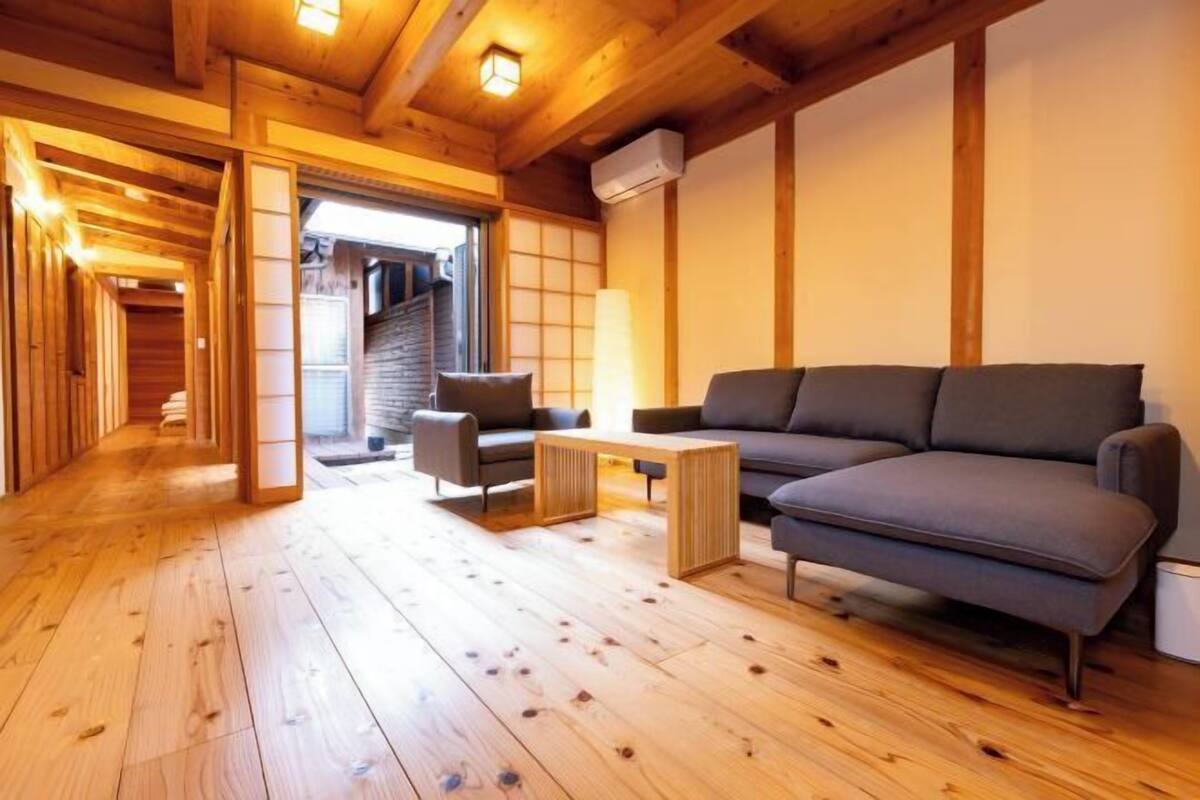 Un interior de madera con un sofá, una mesa y una escalera que lleva a un balcón.