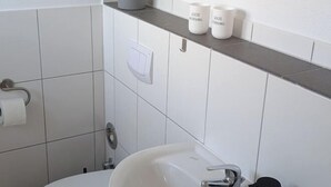 A bathroom with a white sink, a mirror, and a shelf with three white mugs. - Q Apartment No. 1 in BS Life close to the city (Braunschweig)