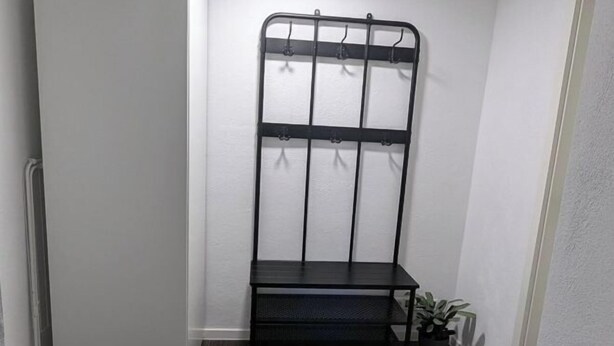 A corner room with a black metal shelf unit against the wall, a small step, and a potted plant. - Q Apartment No. 1 in BS Life close to the city (Braunschweig)