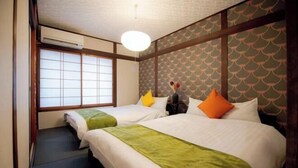 A hotel room with two beds, a window with shoji screens, a ceiling fan, and a patterned wall. - Rakuyado Imazato (Osaka)