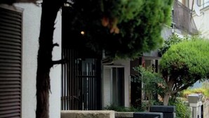 A narrow street with a row of houses, each with a small front garden and a black metal gate. - Rakuyado Imazato (Osaka)