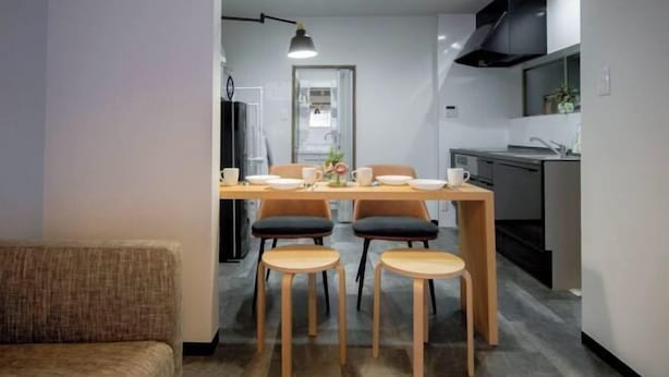 A modern kitchen with a dining area, featuring a wooden table, four chairs, and a pendant light. - Rakuyado Imazato (Osaka)