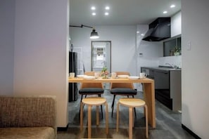 A modern kitchen with a dining area, featuring a wooden table, four chairs, and a pendant light.