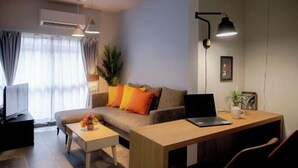 A modern living room with a sofa, coffee table, and a desk with a laptop. - Rakuyado Imazato (Osaka)
