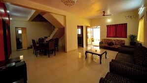 A spacious living room with a staircase, a dining area, and a sofa. - Savitri Bungalow (Dhangarwadi)