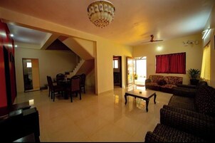 Un amplio salón con escalera, zona de comedor y sofá.