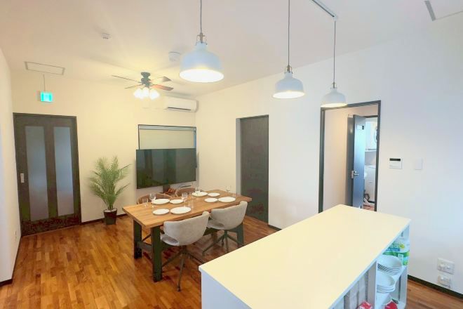 Un comedor moderno con una mesa de madera, sillas, lámparas colgantes y un ventilador de techo.