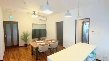 Un comedor moderno con una mesa de madera, sillas, lámparas colgantes y un ventilador de techo.