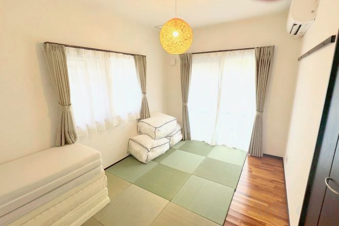 A room with a bed, a sofa, a small table, and a window with curtains.