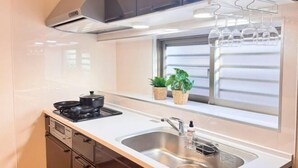 A compact kitchen with a stove, sink, and potted plants. - NewOpen/　NAGO-YA Walking distance to beach Fast WiFi Nature Retreat (Nago)