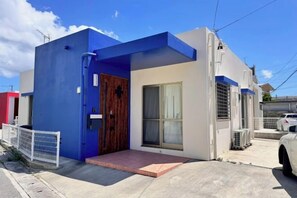Un edificio moderno con facciata blu e bianca, una porta in legno e un piccolo portico.