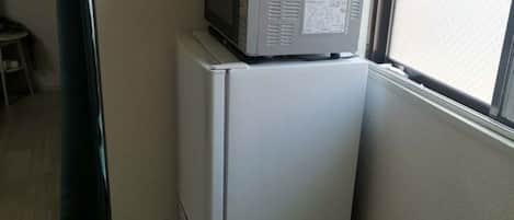 A kitchen with a refrigerator and a microwave on top.
