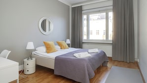 Quarto moderno com cama, mesa de cabeceira, luminária e vista para o exterior.