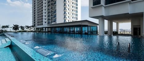A swimming pool with clear blue water, surrounded by modern buildings with large windows.