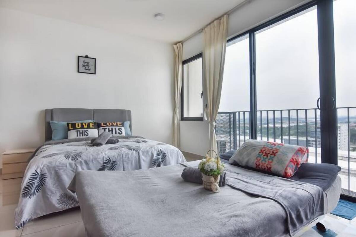 A modern bedroom with two beds, a large window with curtains, and a view of the city.
