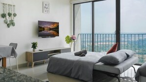 Ein modernes Schlafzimmer mit großem Fenster, einem Flachbildfernseher und einem Balkon mit Blick auf die Stadt.