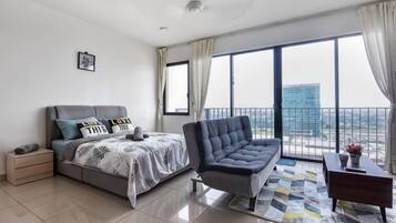 A modern bedroom with a bed, a sofa, a nightstand, and a view of the city.