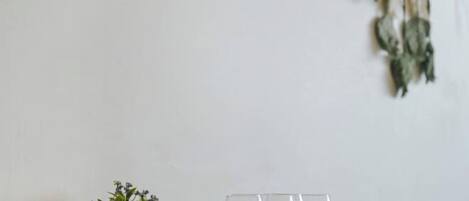 A framed picture on a wall, a macrame wall hanging, and a small plant.