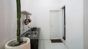 Cocina compacta con pileta, cocina y ollas colgadas.