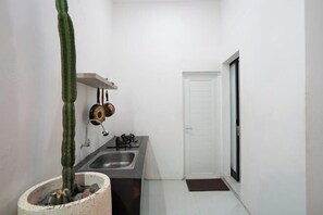 Cocina compacta con pileta, cocina y ollas colgadas.