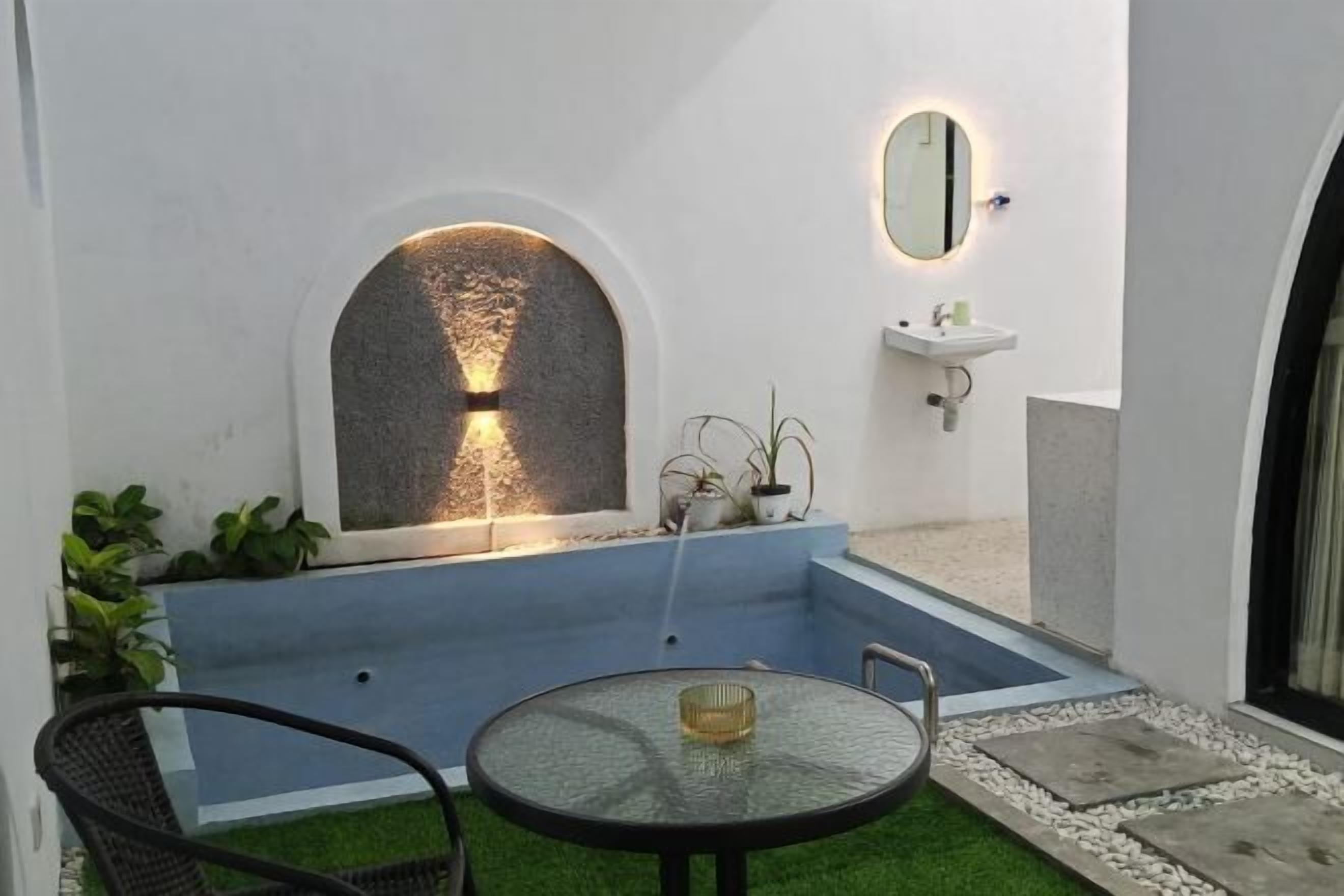 A courtyard with a fountain, a round table, and a sink.