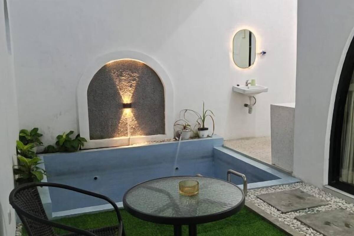 A courtyard with a fountain, a round table, and a sink.