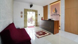 Un área de recepción con un mostrador, un sofá rojo y una pared de madera.