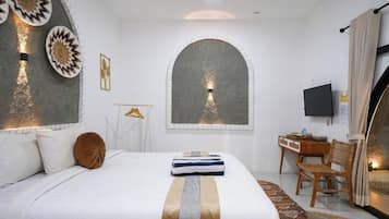 A bedroom with a large bed, a desk, and a television.