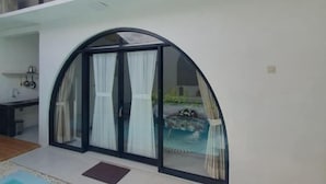 Una habitación moderna con una puerta de vidrio curva que da a una zona de piscina.