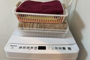Een wasmachine met een mand en een handdoek erop.