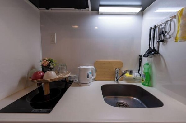 A compact kitchen with a sink, a kettle, a cutting board, and a small countertop area. - FAREakihabara　ONE (Tokyo)